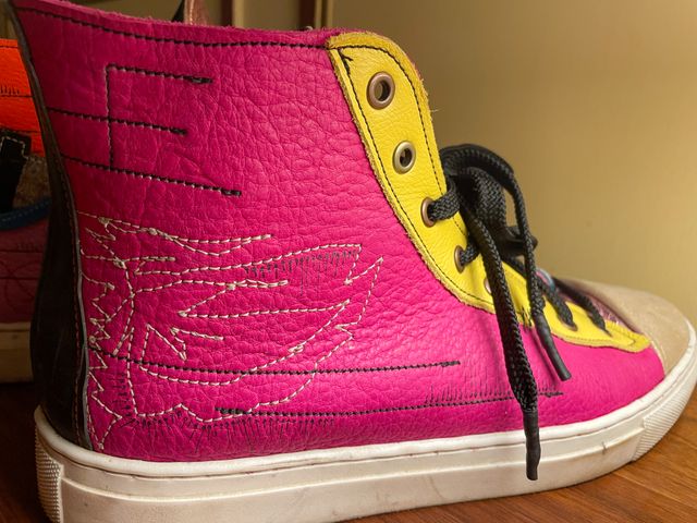Closeup outside right shoe
in magenta leather with yellow lace panel,
tan-stitched open-wing moth sketch,
with black lines and arrows.