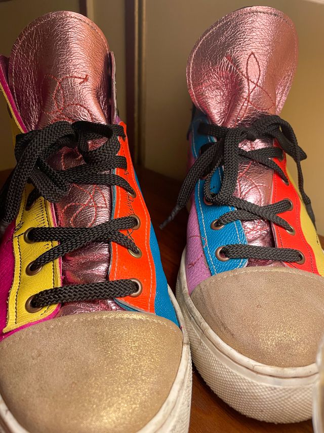 Closeup front of the pair,
gold leather toe caps,
and rose gold tongues with red scribble-stitching.