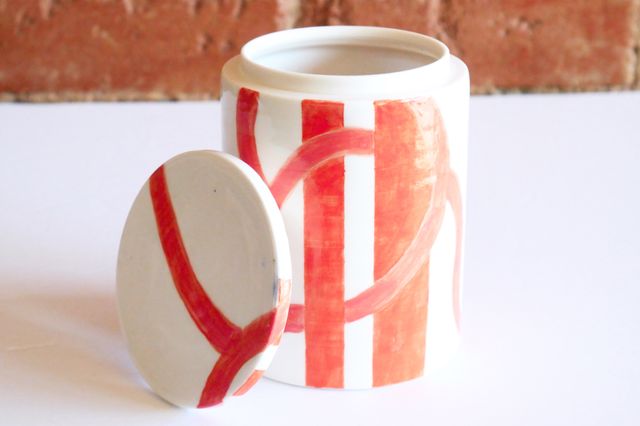 White jar with orange stripes and swirls that match our wall.